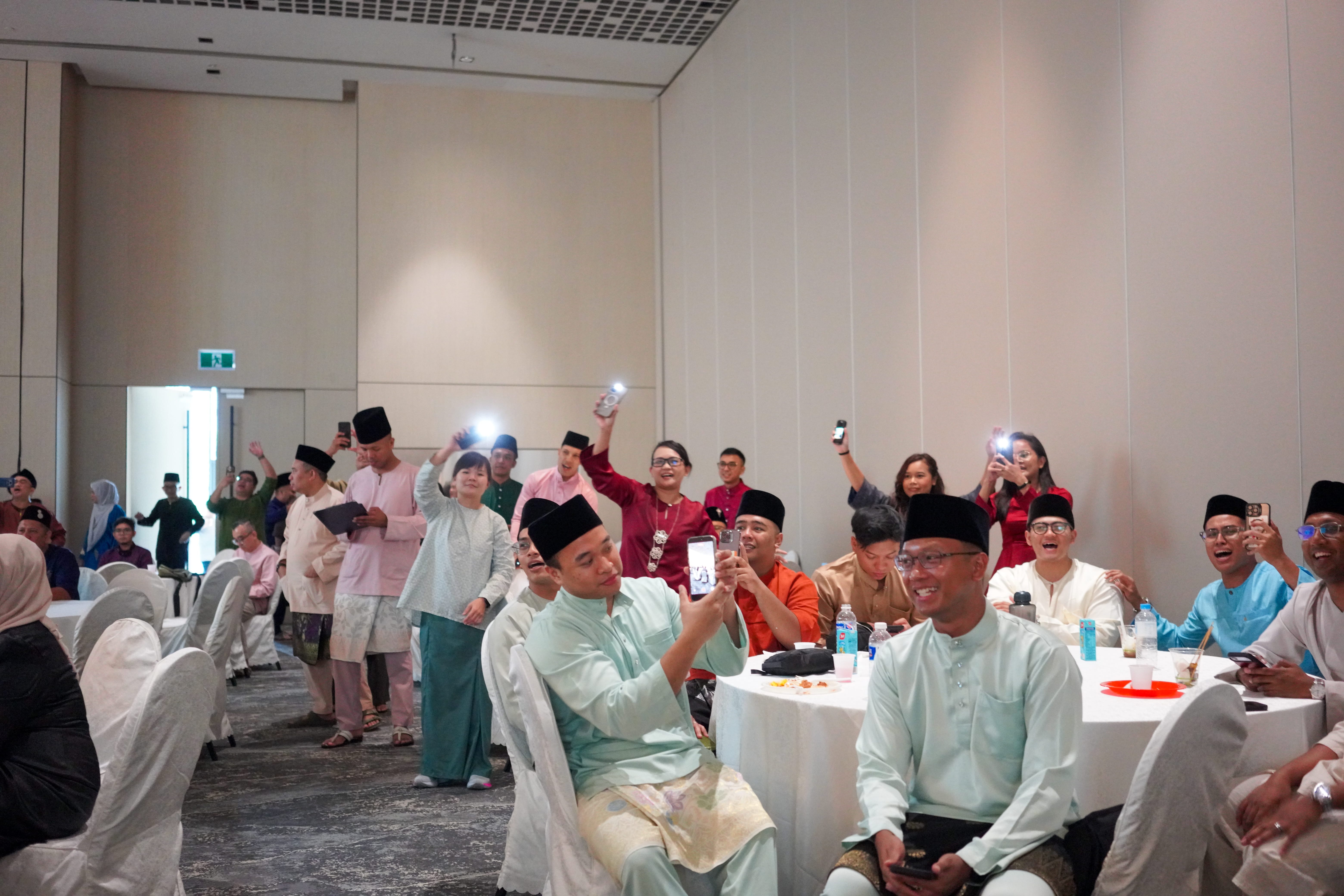 Guests raising mobile phones and joining an interactive activity during the entertainment programme.